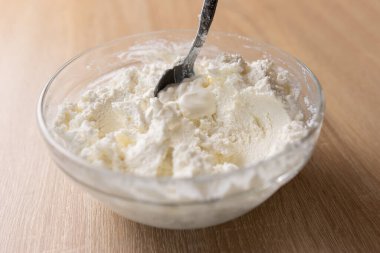 Ekşi süt peynirine ekşi krema eklenir ve karıştırılır.