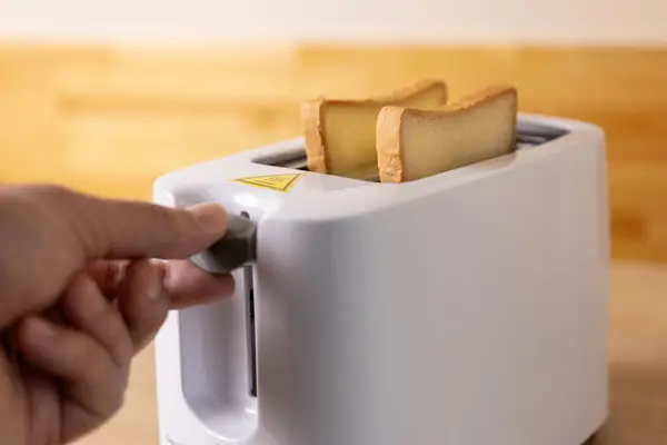 To make toast, bread is loaded into an electric