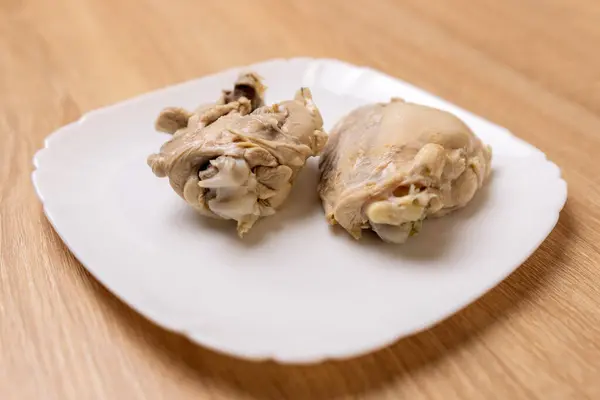 Boiled chicken meat is laid out on a white plate. Cooking chicken dishes.