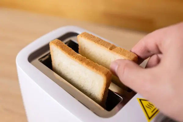 To make toast, bread is loaded into an electric