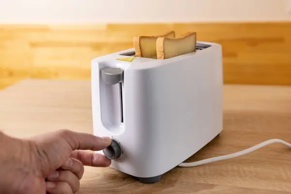 To make toast, bread is loaded into an electric toaster.