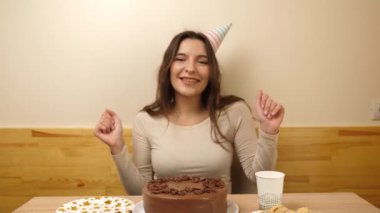 Masanın önünde elinde şenlikli bir pastayla oturan bir kız. 17 numaralı pastaya mum takılmış. Doğum günü kutlaması konsepti.
