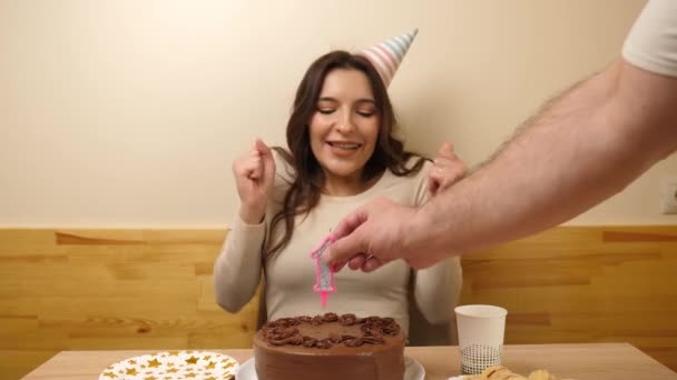 女の子がお祝いのケーキを持ってテーブルの前に座っていて その中に19という数字の形をしたろうそくが立ち往生している 誕生日のお祝いのコンセプト — ストック動画