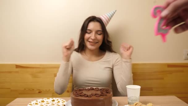 一个女孩坐在桌前 手里拿着一个喜庆的蛋糕 桌上插着一支22号的蜡烛 庆祝生日的概念 — 图库视频影像