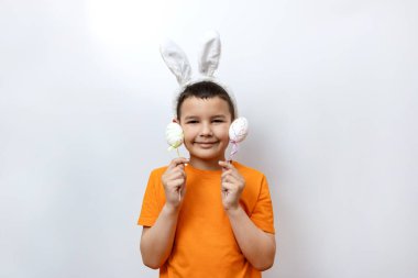 Tavşan kulaklı ve elinde süslü Paskalya yumurtaları tutan bir çocuk..