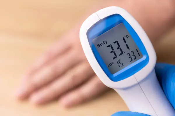 人間の体温は遠隔温度計によって測定されます ストックフォト