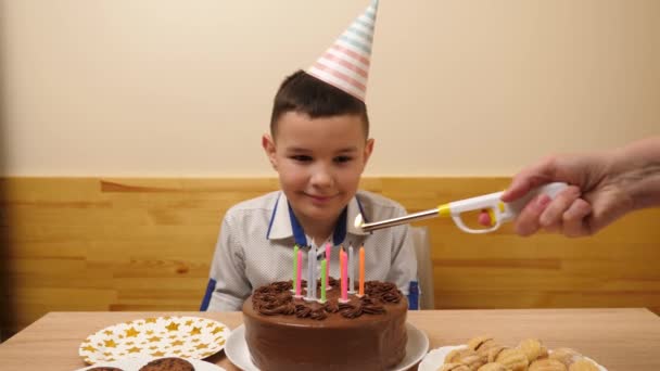 男はろうそくが点灯するお祝いのケーキを持ってテーブルの前に座っている 誕生日のお祝いコンセプト — ストック動画