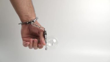 Kelepçeli bir adam elektrik ampulüne bağlıdır. Enerji bağımlılığı kavramı.