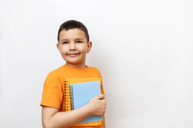 Beyaz arka planda turuncu tişörtlü bir adam ders kitaplarını elinde tutuyor. Çocukların eğitim süreci.