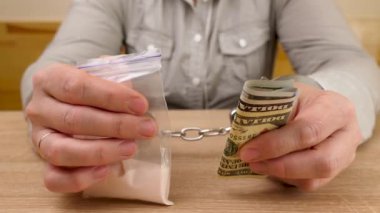 Uyuşturucu ve dolarlarla kelepçelenmiş bir kadın. Uyuşturucu bağımlılığı kavramı. Uyuşturucu suçu..