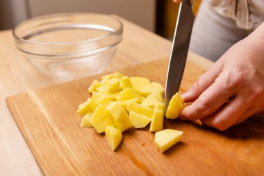 Çiğ patatesler bıçakla küp şeklinde kesilir. Sebze yemeği hazırlama.