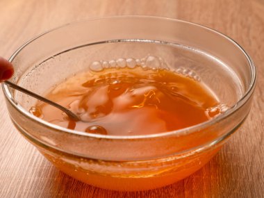 Sıcak su bir kaseye dökülüyor, içinde yeşil jöle eritiliyor. Jelatin tatlılarının hazırlanması.