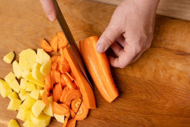 Çiğ havuç, bıçakla küp küp kesilir. Sebze yemeği hazırlama.