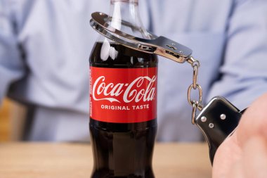 Bir adam bir şişe Coca-Cola 'ya kelepçelendi. Karbonatlı tatlı içeceklere bağımlılık konsepti. Ukrayna. Lviv (05.09.24)