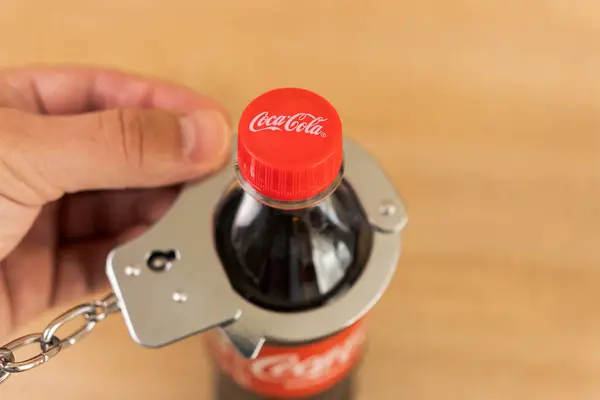 Bir adam bir şişe Coca-Cola 'ya kelepçelendi. Karbonatlı tatlı içeceklere bağımlılık konsepti. Ukrayna. Lviv (05.09.24)