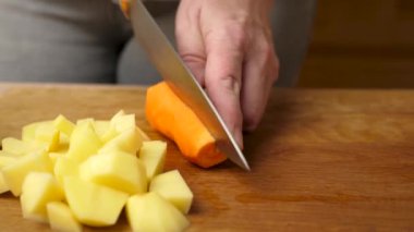 Çiğ havuç, bıçakla küp küp kesilir. Sebze yemeği hazırlama.