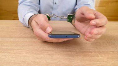 Akıllı telefonlu kelepçeli bir adam. Akıllı telefon bağımlılığı konsepti. Yavaş çekim