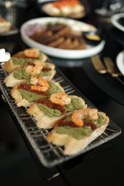 Sandwiches with sauce and shrimp on the buffet table. clipart