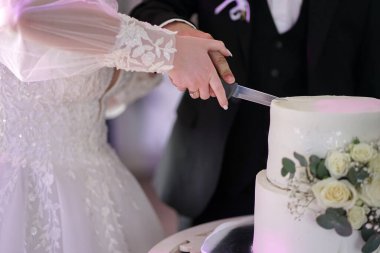 Tahta bir standın üzerinde beyaz güllerle süslenmiş güzel beyaz bir düğün torusu. Düğün kutlaması.