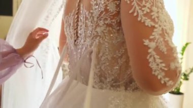 Gelinin bir arkadaşı elbisenin korsesini sıkmasına yardım ediyor. Düğün hazırlıkları..