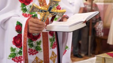 Rahip elinde bir haç ve elinde bir kitapla dua okur..