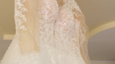 Güzel beyaz bir gelinlik bir avizeye asılı. Düğün hazırlıkları..