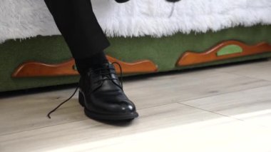 Bir adam ayakkabı bağcıklarını siyah deri ayakkabılara bağlıyor. Şık erkek ayakkabıları..