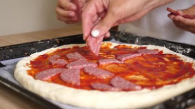 Salam ve zeytin pizzaya eklenir. Evde pizza pişirmek..