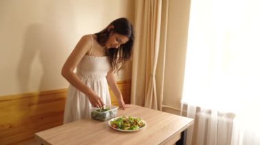 Kız sebze salatasına salatalık ve domates ekliyor..