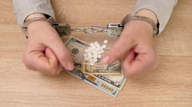 İlaç ve dolarlarla kelepçelenmiş bir kadın. Uyuşturucu bağımlılığı kavramı. Uyuşturucu suçu. yavaş çekim