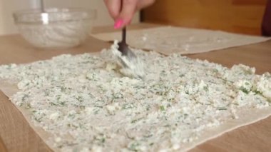 Pide ekmeğine peynir ve yeşillik koy. Bir rulo hazırlama.