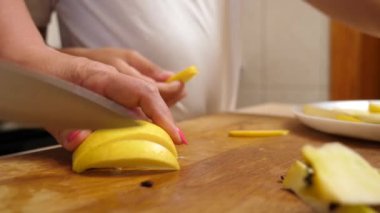 Olgun sarı bir elma bıçakla parçalara ayrılır..