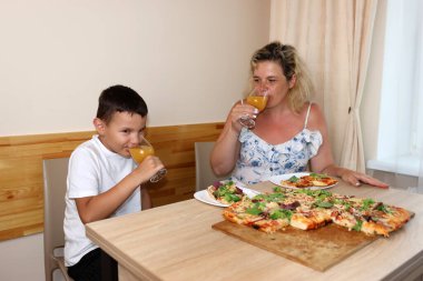 Anne ve oğlu taze pişmiş pizzanın tadını çıkarıyorlar. Evde yemek yaparız..