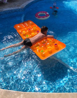 Havuzda şişme yatakta bir çocuk..