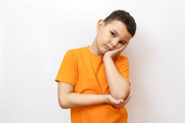 Turuncu tişörtlü bir adam elini yanağından tutuyor..