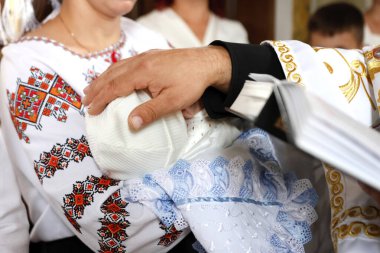Bir rahip, vaftiz töreni sırasında yeni doğmuş bir bebeği eliyle kutsar..