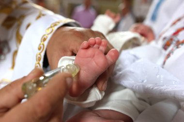 The priest performs the rite of baptism and anointing. clipart