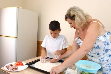 Anne ve oğlu evde pizza pişiriyor..