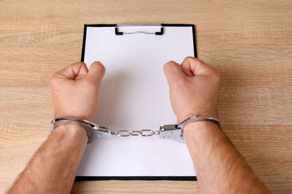 Человек в наручниках с табличкой с чистым листом. Копирование места преступления или наркомании.