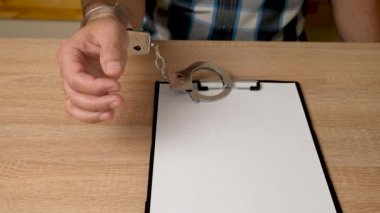 Elleri kelepçeli, tabletli, boş çarşaflı bir adam. Suç ya da bağımlılık üzerine kopyalama alanı.