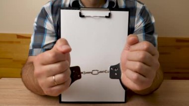 Elleri kelepçeli, tabletli, boş çarşaflı bir adam. Suç ya da bağımlılık üzerine kopyalama alanı.