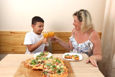 Anne ve oğlu taze pişmiş pizzanın tadını çıkarıyorlar. Evde yemek yaparız..