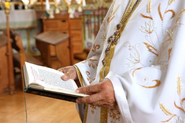 Dua sırasında, rahip Kiril alfabesiyle bir kitap okur..