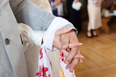 Church wedding ceremony. The hands of the newlyweds are tied with an embroidered cloth. clipart