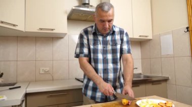 Bir adam mutfakta taze şeftali yiyor..