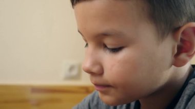 Bir çocuk masada otururken yoğurtla mısır gevreği yiyor..