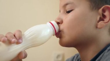 Çocuk masada otururken yoğurt içer..