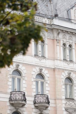 Kemerli pencereleri ve yuvarlak balkonları olan tarihi bir binanın ön cephesi..