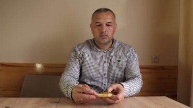 Bir adam masada otururken çikolata yiyor..