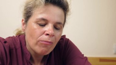 Bir kadın masada oturmuş patlamış mısır yiyor..